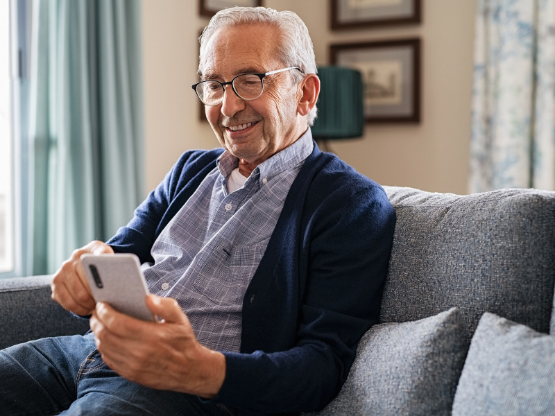 An older man using his mobile phone at home.