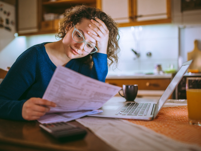 A woman looking through household bills at a table.