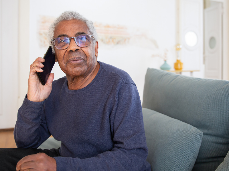 An older man making a phone call at home.